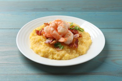 Photo of Plate with fresh tasty shrimps, bacon and grits on light blue wooden table