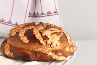 Photo of Korovai on white table against light background. Ukrainian bread and salt welcoming tradition