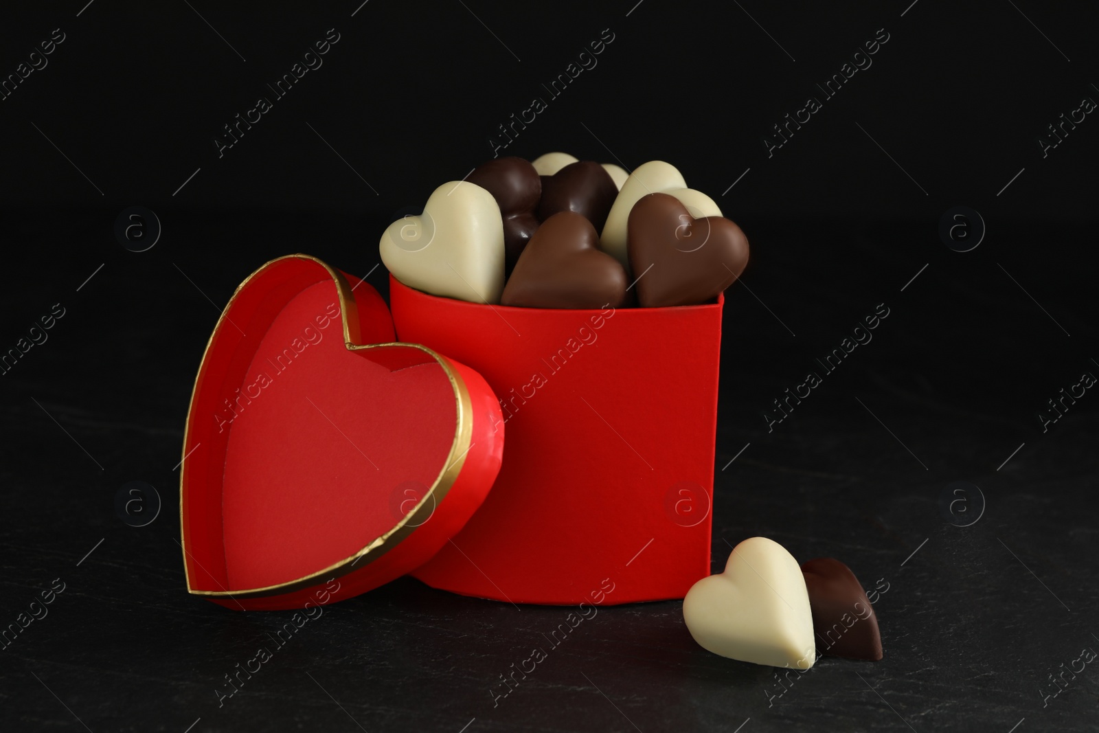 Photo of Beautiful heart shaped chocolate candies in box on black background