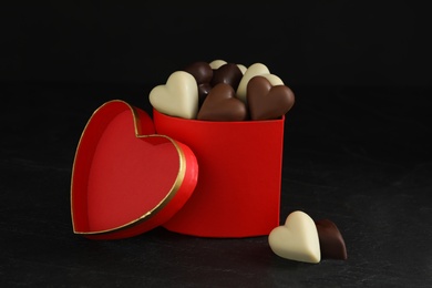 Photo of Beautiful heart shaped chocolate candies in box on black background