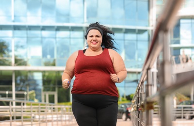 Beautiful overweight woman running outdoors. Fitness lifestyle