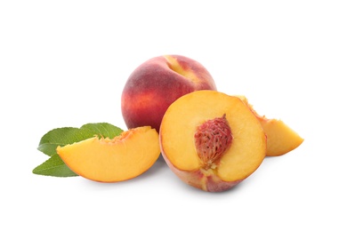 Whole and cut ripe peaches with leaves isolated on white