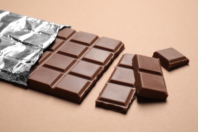 Pieces of delicious chocolate bar on beige background