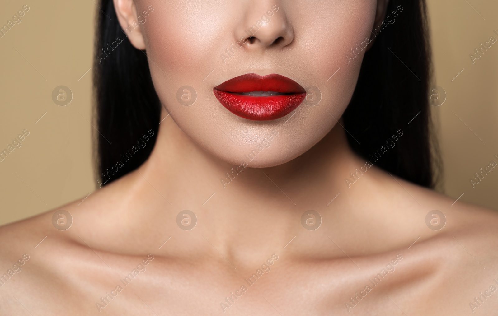 Image of Young woman wearing beautiful red lipstick on beige background, closeup