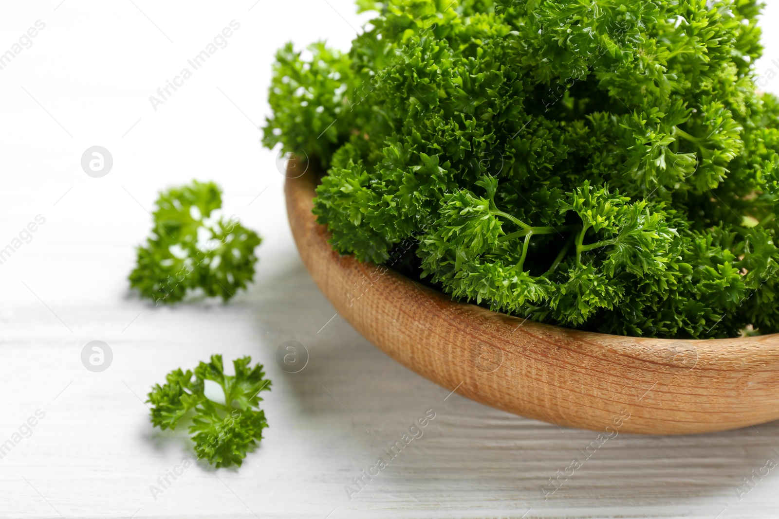 Photo of Fresh curly parsley on white wooden table, closeup