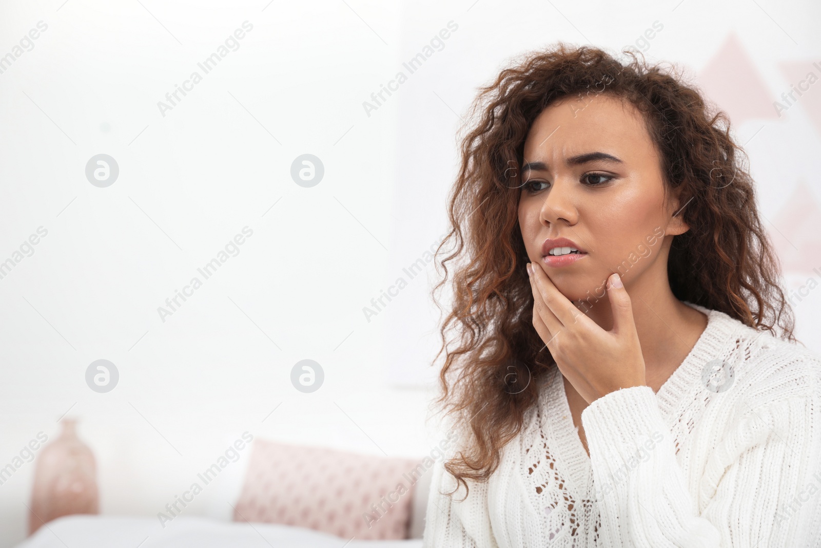 Photo of African-American woman suffering from tooth ache at home. Space for text