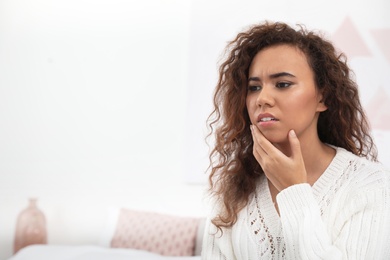 African-American woman suffering from tooth ache at home. Space for text