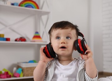 Photo of Cute little boy in headphones listening to music at home