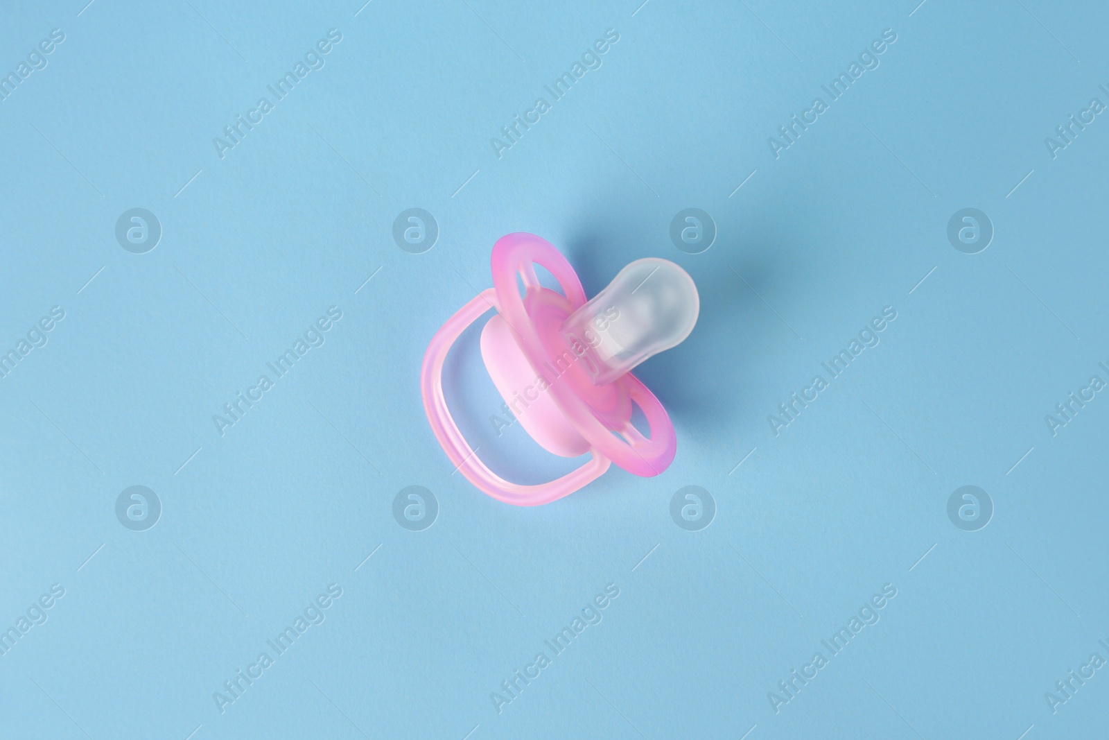 Photo of One new baby pacifier on light blue background, top view