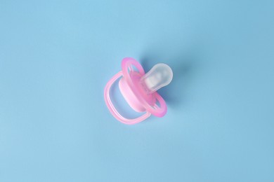 Photo of One new baby pacifier on light blue background, top view