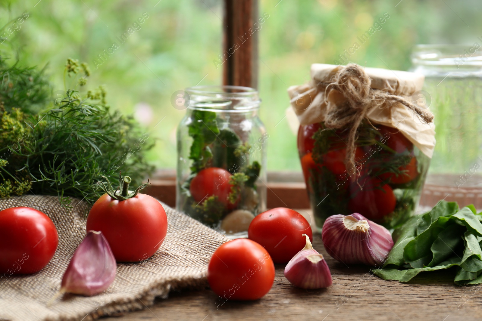 Photo of Glass jars, fresh vegetables and herbs on wooden table indoors. Pickling recipe