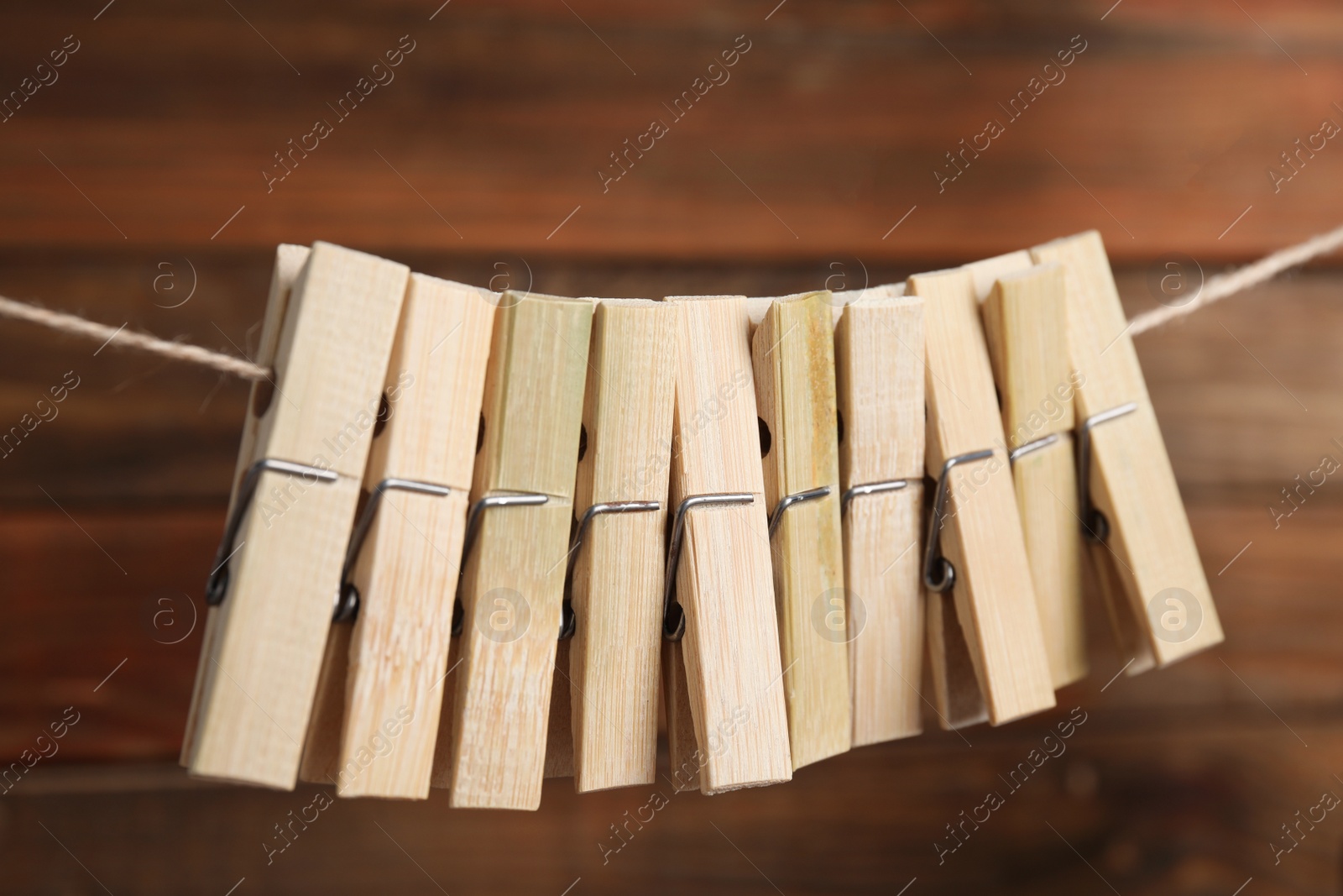 Photo of Many clothespins on rope against wooden background, closeup