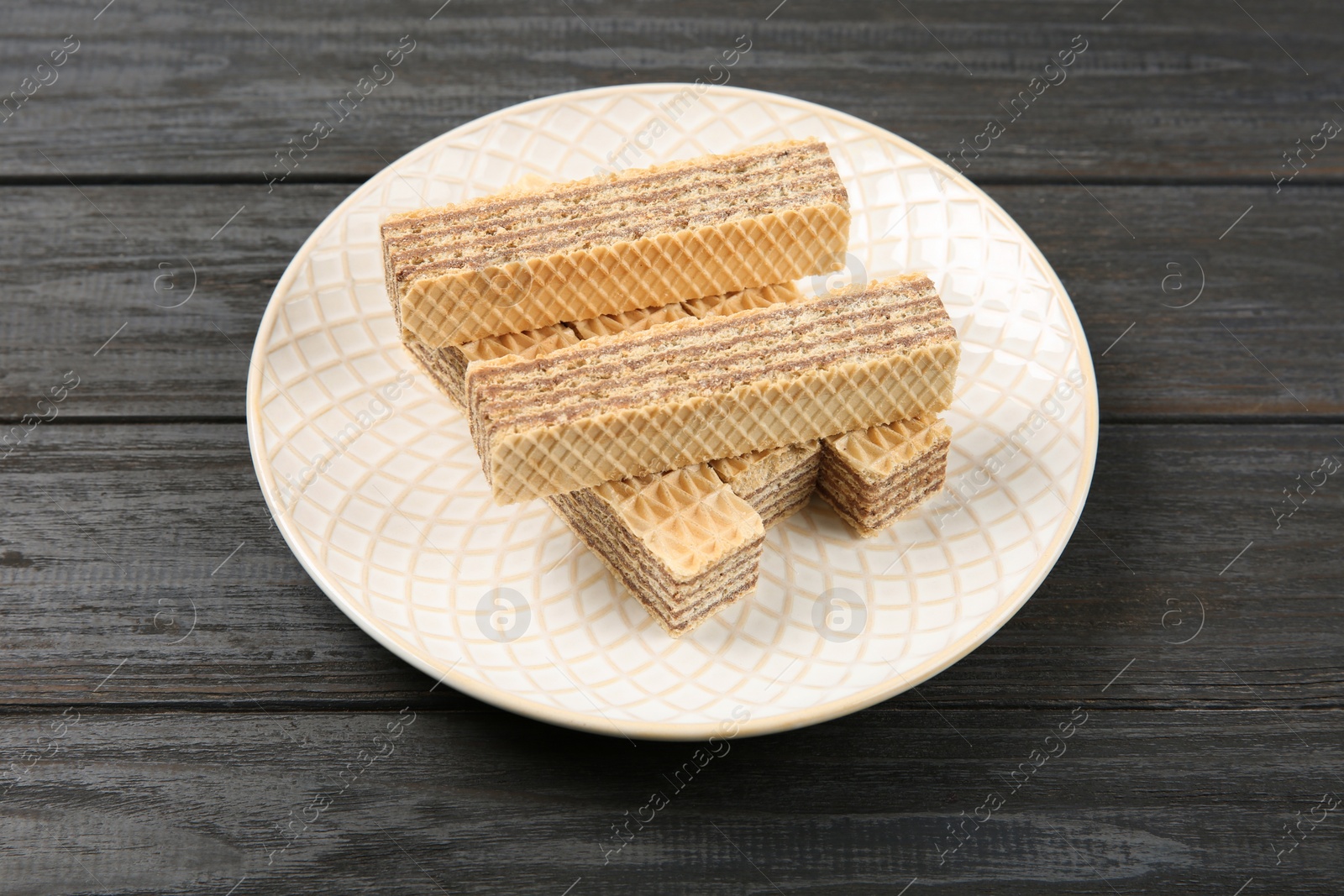 Photo of Plate with delicious crispy wafers on wooden table