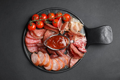 Photo of Different types of sausages with sauce served on black background, flat lay