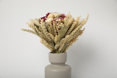 Beautiful bouquet of dry flowers in ceramic vase on white background