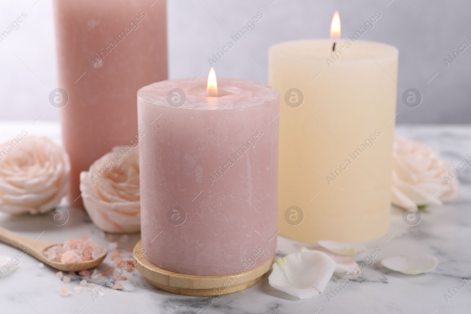 Photo of Spa composition with burning candles, flowers and sea salt on white marble table