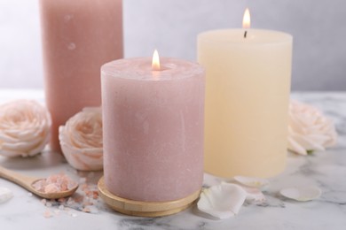 Photo of Spa composition with burning candles, flowers and sea salt on white marble table