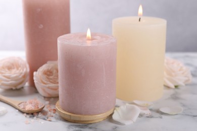 Spa composition with burning candles, flowers and sea salt on white marble table