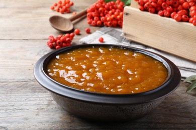 Photo of Delicious rowan jam in bowl on wooden table