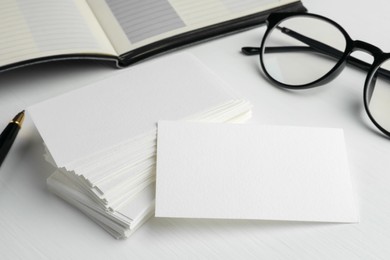 Photo of Blank business cards and glasses on white table, closeup. Mockup for design