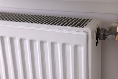 Photo of Modern radiator on white wall, closeup. Central heating system