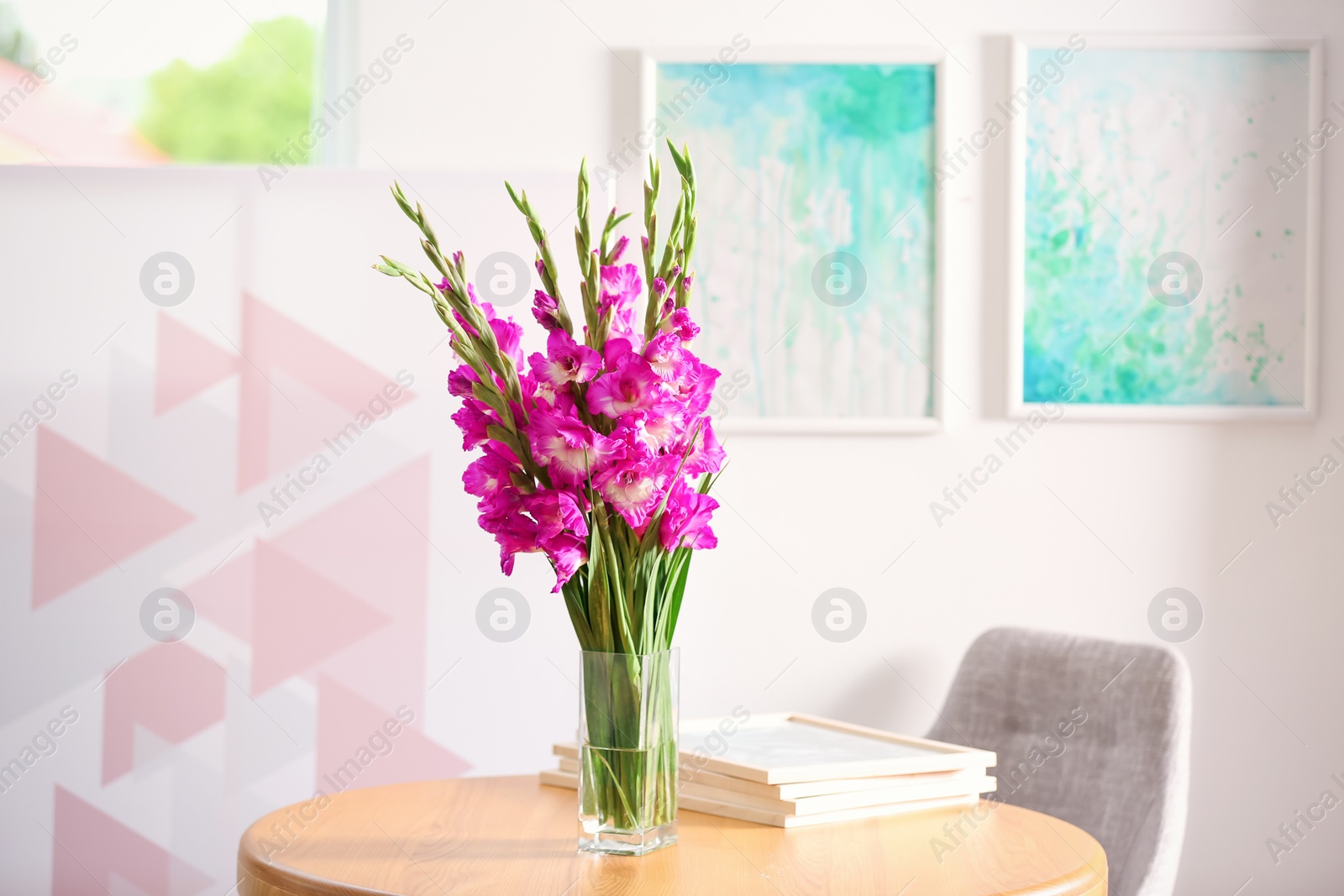 Photo of Vase with beautiful pink gladiolus flowers on wooden table in room, space for text