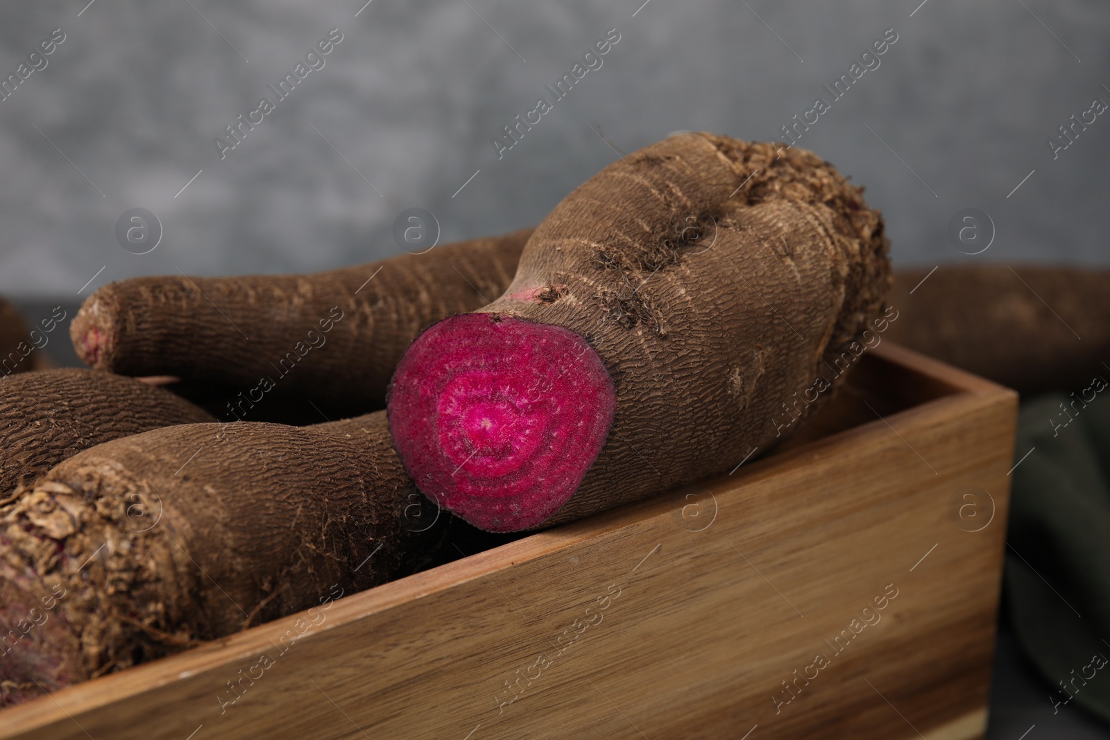 Photo of Whole and cut red beets in wooden crate, closeup