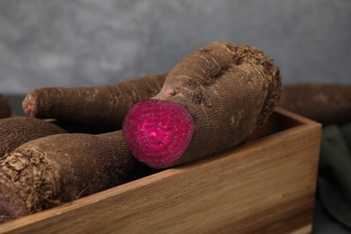 Photo of Whole and cut red beets in wooden crate, closeup