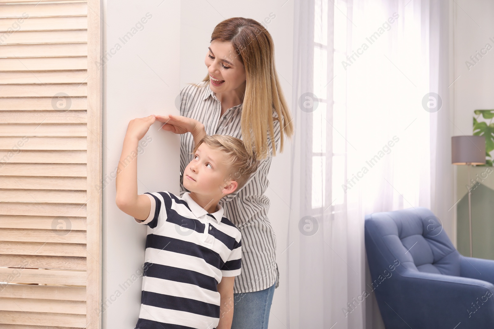 Photo of Young woman measuring her son's height at home