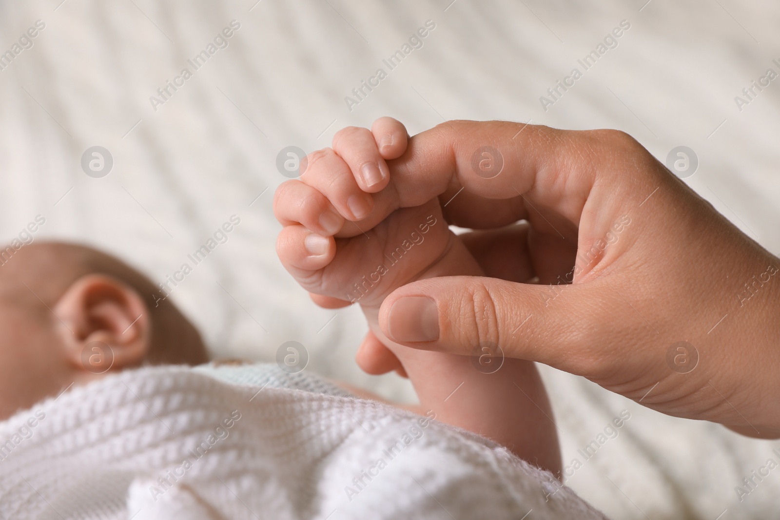 Photo of Mother and her newborn baby on white knitted plaid, closeup