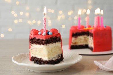 Photo of Piece of bento cake with tasty cream and burning candles on wooden table, closeup