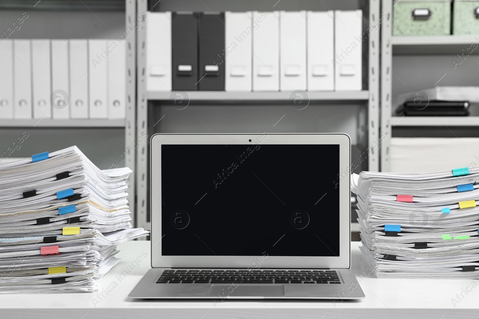 Photo of Laptop and documents on desk in office. Space for text
