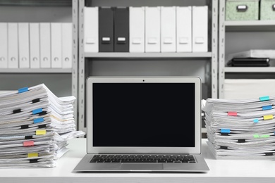 Laptop and documents on desk in office. Space for text