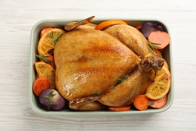 Delicious chicken with oranges and vegetables on white wooden table, top view