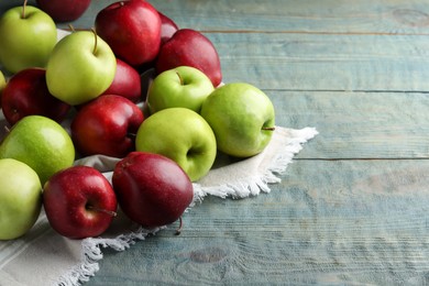 Photo of Fresh ripe red and green apples on light blue wooden table, space for text