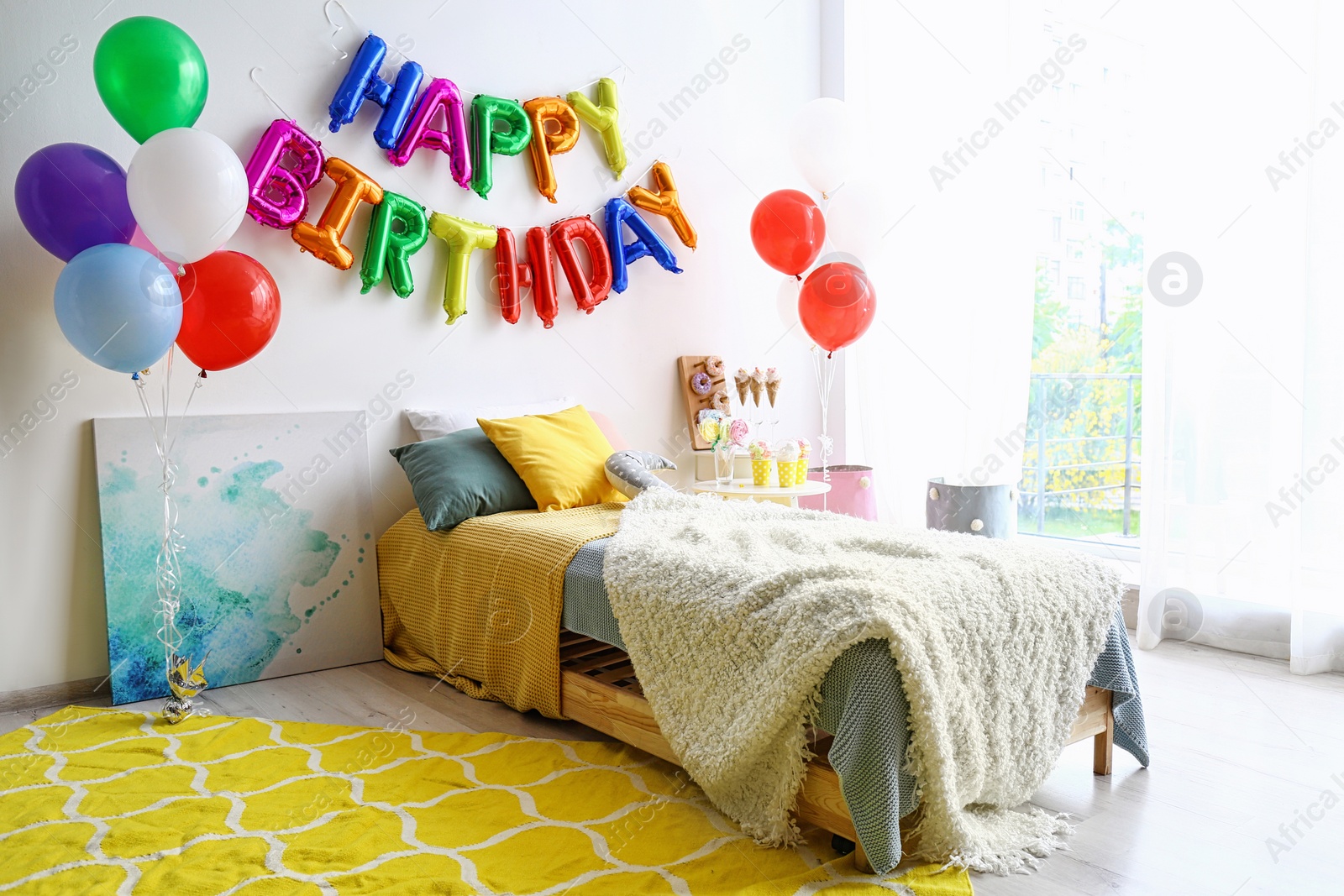 Photo of Phrase HAPPY BIRTHDAY made of colorful balloon letters in modern bedroom