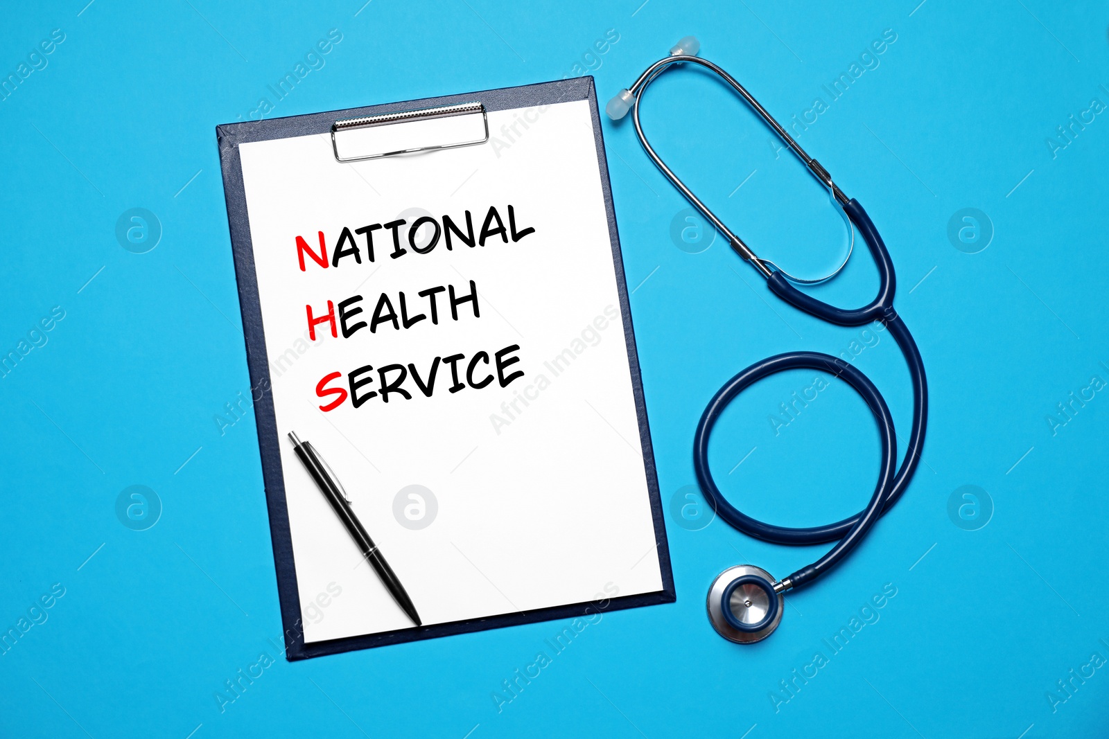 Image of National health service (NHS). Clipboard with text, pen and stethoscope on light blue background, top view