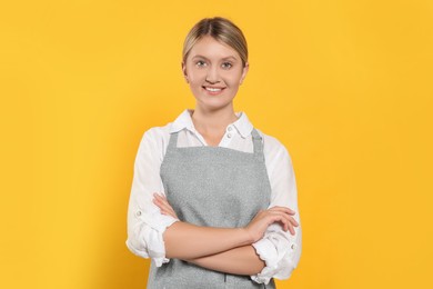 Beautiful young woman in clean apron with pattern on orange background