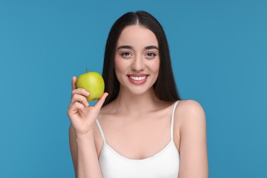 Photo of Beautiful young woman with apple on light blue background