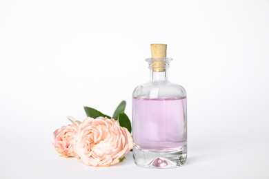 Photo of Bottle of essential oil and roses on white background