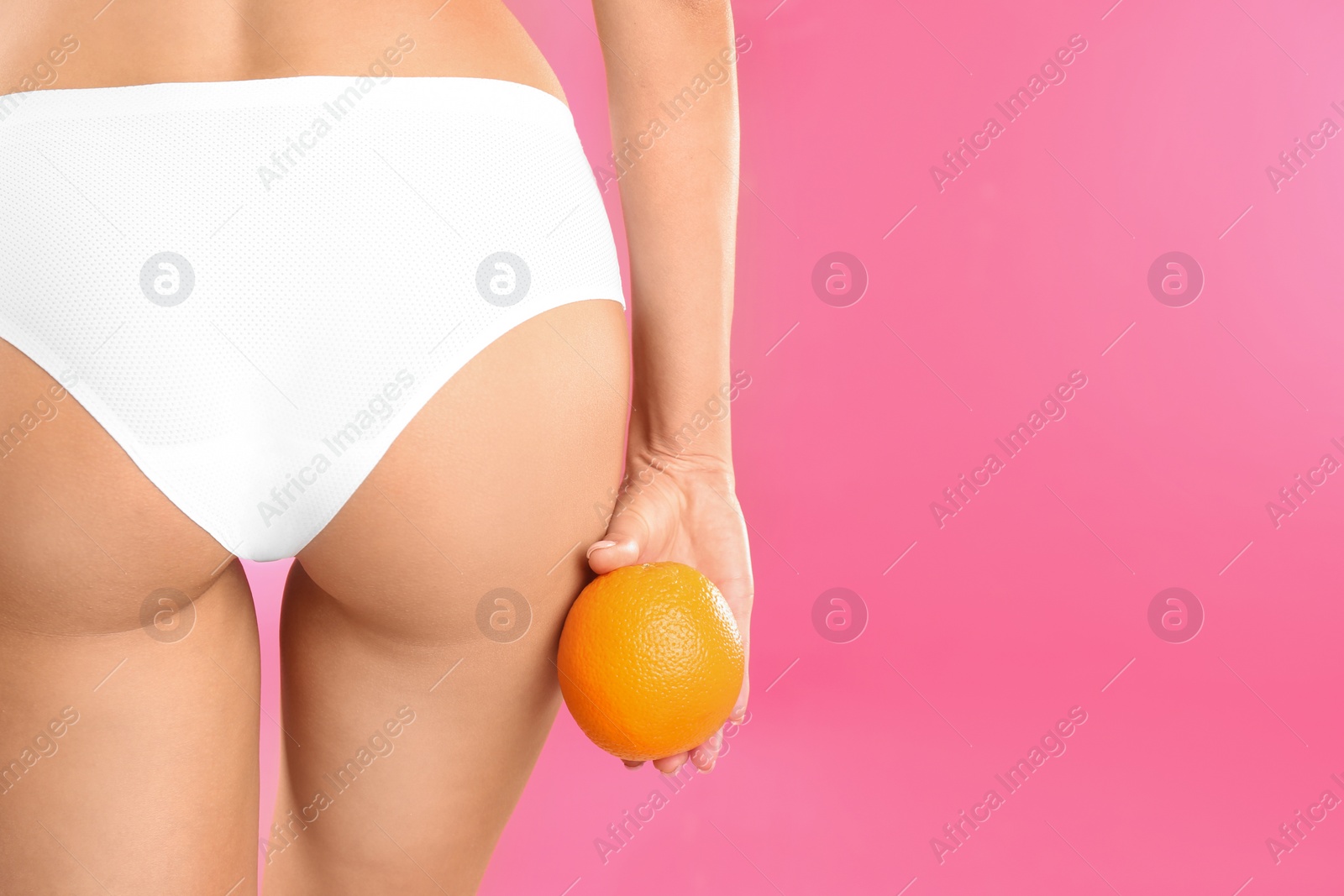 Photo of Closeup view of slim woman in underwear with orange on color background, space for text. Cellulite problem concept