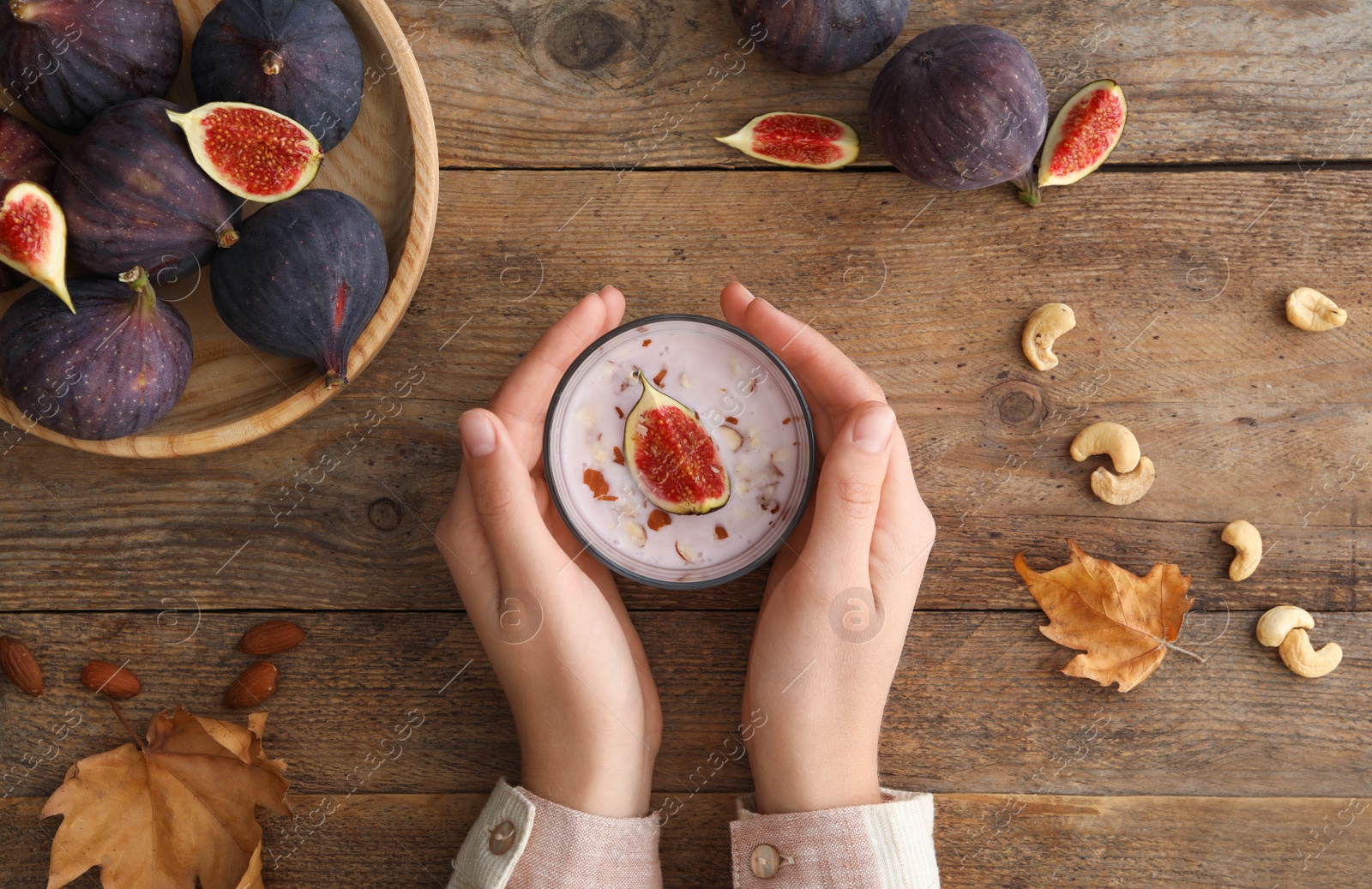 Photo of Woman with delicious fig smoothie at wooden table, top view