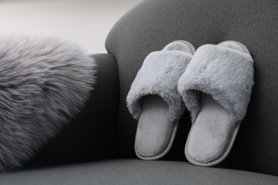 Photo of Soft grey slippers and faux fur on sofa