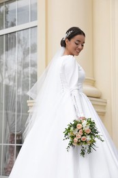 Photo of Young bride wearing wedding dress with beautiful bouquet outdoors