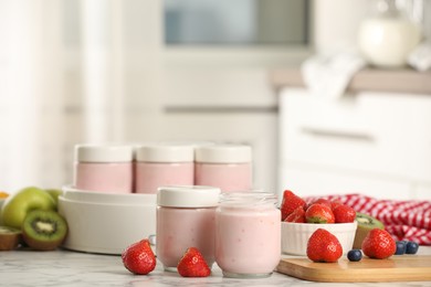 Photo of Modern yogurt maker with full jars and different fruits on white marble table indoors