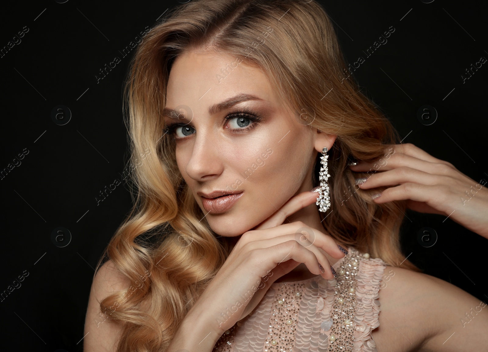 Photo of Beautiful young woman with elegant jewelry on dark background