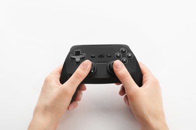 Photo of Young woman holding video game controller on white background, closeup