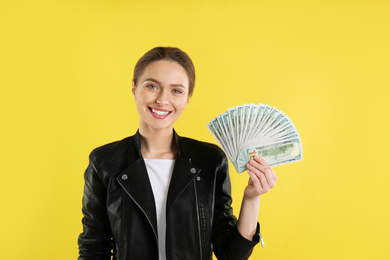 Young woman with money on yellow background