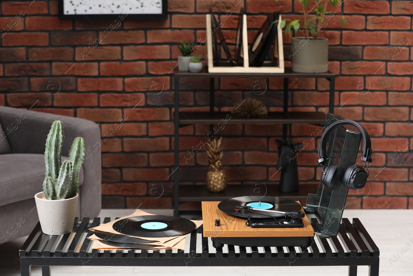Photo of Stylish turntable with vinyl records, headphones and houseplant on table indoors