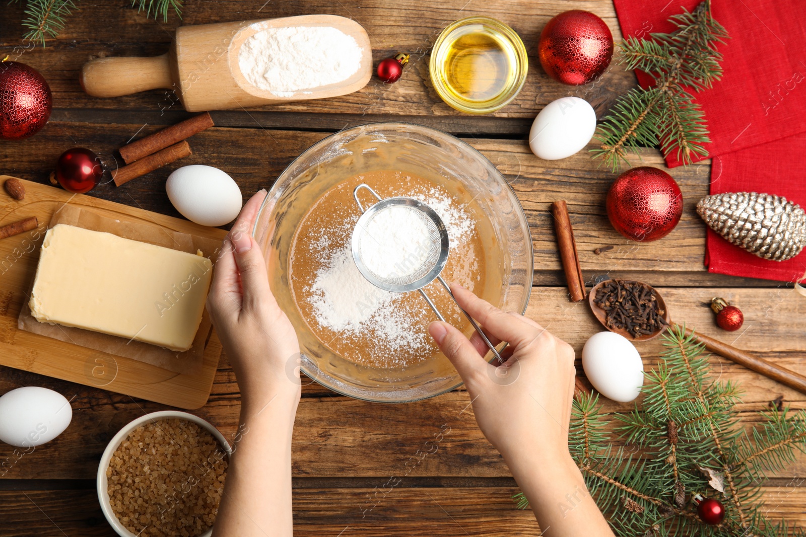 Photo of Woman cooking traditional Christmas cake at wooden table with ingredients, top view